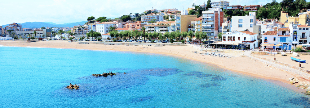 Luftaufnahme eines Strandes und des Meeres auf Gran Canaria mit Gebäuden im Hintergrund. Erlebe einen Urlaub auf den Kanarischen Inseln und genieße Strand und Sonne das ganze Jahr über